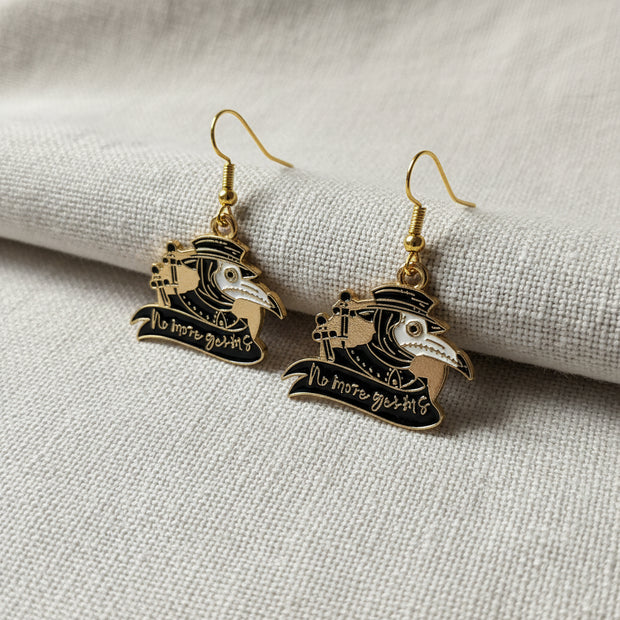 Pair of gold and black plague doctor earrings on a light background