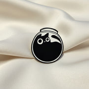 Black and white circular object with a cat silhouette on a beige surface