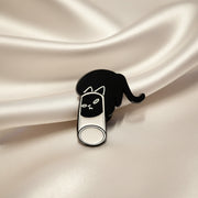 Black and white cat-shaped pin on a textured beige background