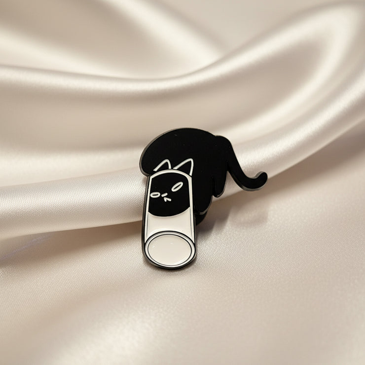Black and white cat-shaped pin on a textured beige background
