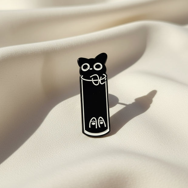 Black cat pin with white details on a light gray background