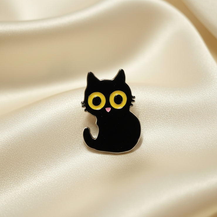 Black cat-shaped pin with yellow eyes and a pink heart on a light gray background