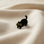 Black cat-shaped object with yellow eyes on a light gray background
