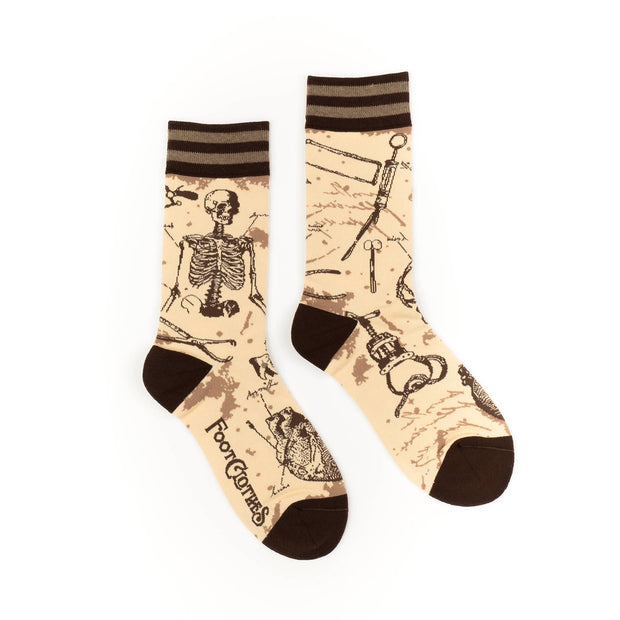 Pair of socks with skeleton and medical tool design on a beige background