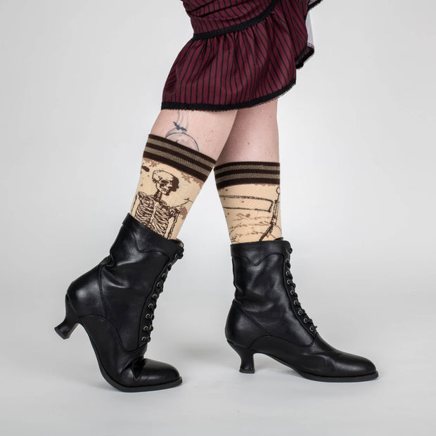 Person wearing black high-heeled boots and patterned knee-high socks with a white background