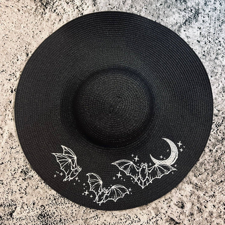 Black sun hat with bat and moon designs on a textured surface