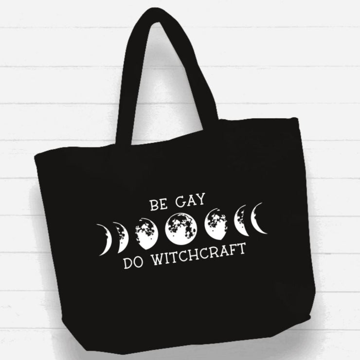 Black tote bag with white text and moon phases on a wooden surface
