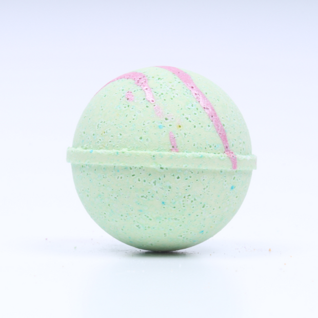 Green bath bomb with pink swirl on a white background