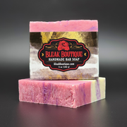 A labeled bar of pink, purple and white Castle Gardens Handmade Vegan Bar Soap on a dark background. Scent notes of Lilac Lily and Jasmine.