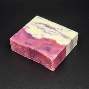 A bar of pink, purple and white Castle Gardens Handmade Vegan Bar Soap on a dark background. Scent notes of Lilac Lily and Jasmine.