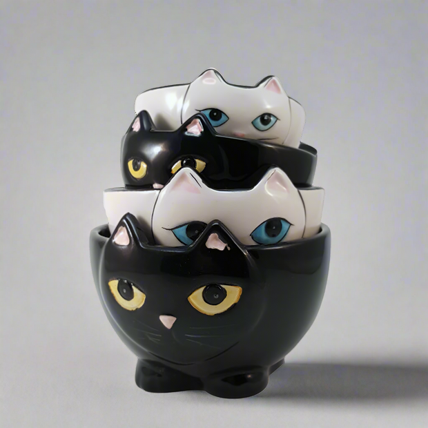 Stack of cat-shaped ceramic bowls with different colored eyes on a white background