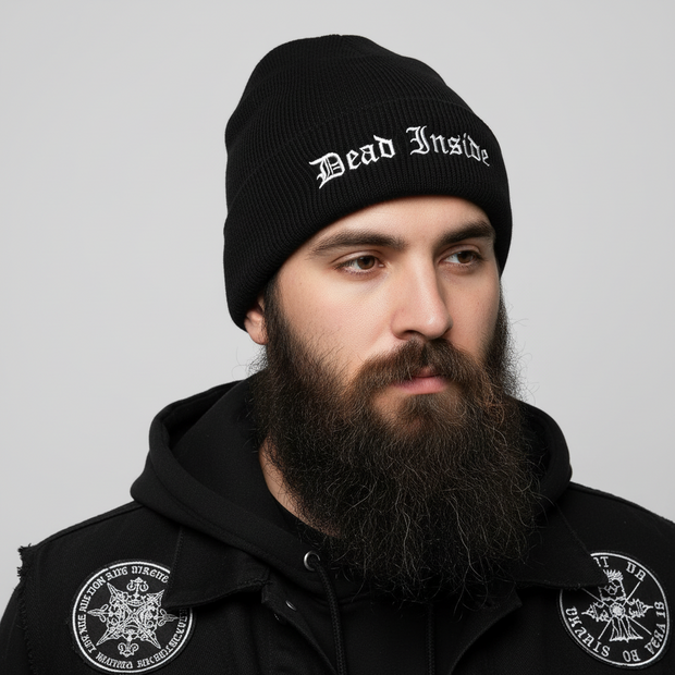 Man wearing a black beanie with 'Dead Inside' text and black jacket with logos on a gray background