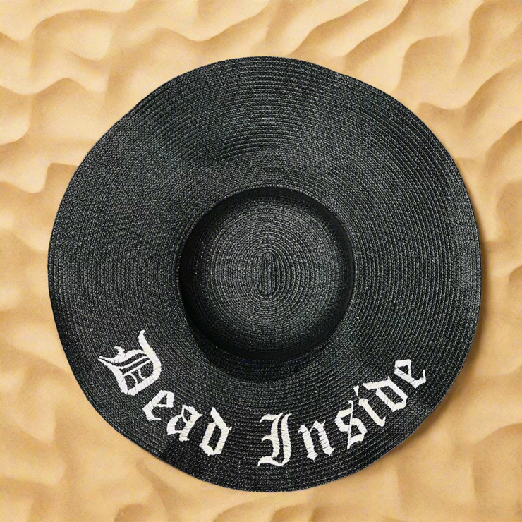 Black straw hat with 'Dead Inside' text on a beach sand background
