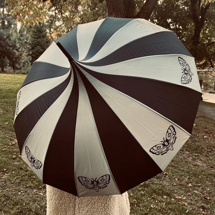 Umbrella with moth designs on a stand outdoors