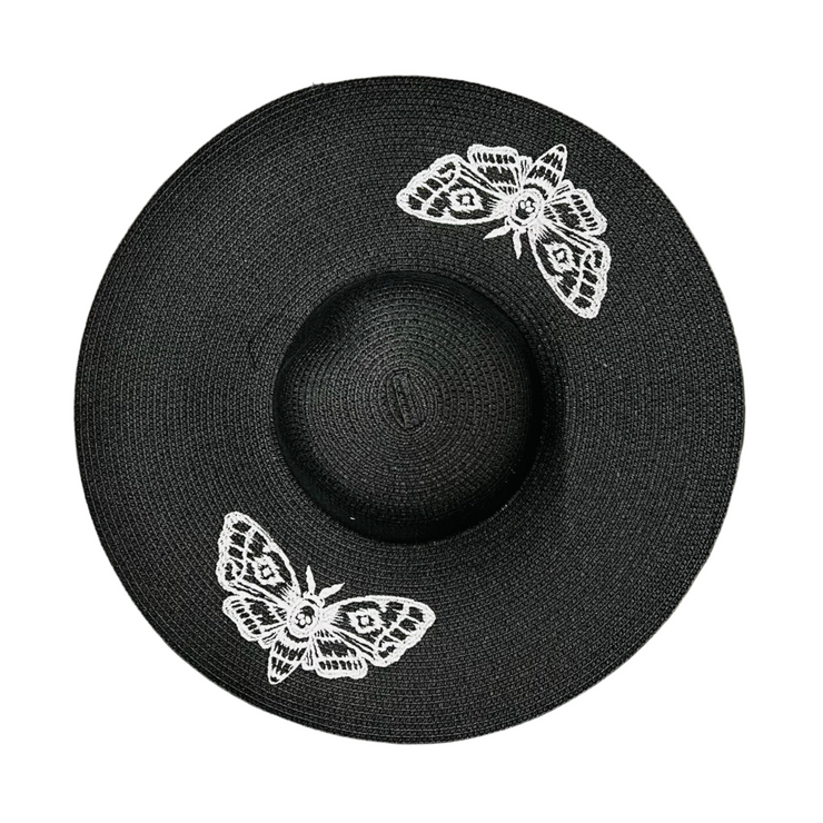 Black straw hat with white moth designs on a white background