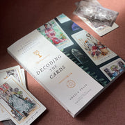Book titled 'Decoding the Cards' by Sheila Ellis with tarot cards on a brown surface