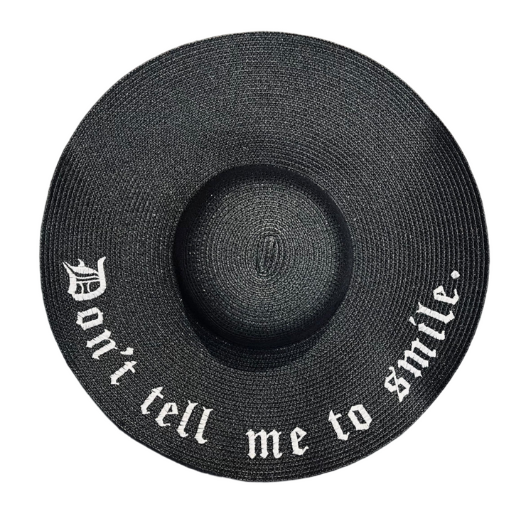 Black straw hat with 'Don't tell me to smile' text on a white background