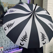 Black and gray striped umbrella with designs held by a person in front of a store window.