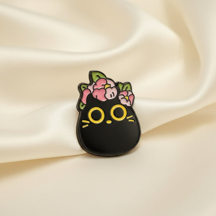 Black cat-shaped pendant with floral designs on a light gray background