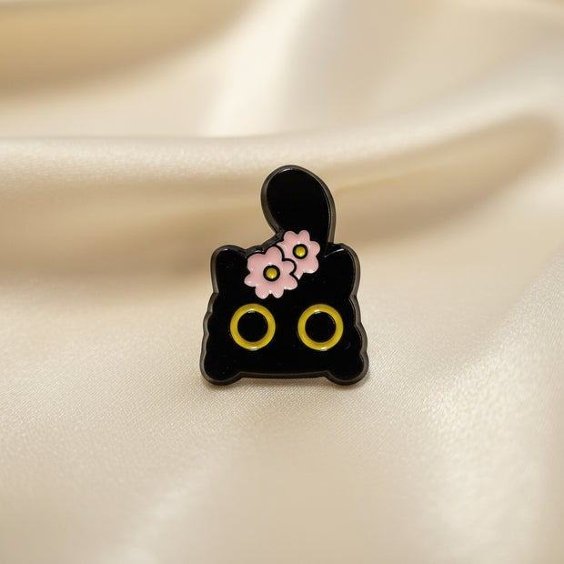 Black cat shaped pin with pink flowers on a light background
