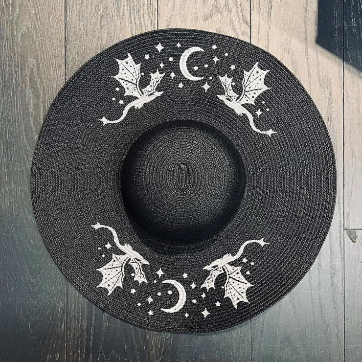 Black hat with white dragon and moon designs on a wooden surface