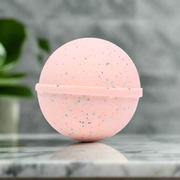 Pink bath bomb with speckles on a marble tile background