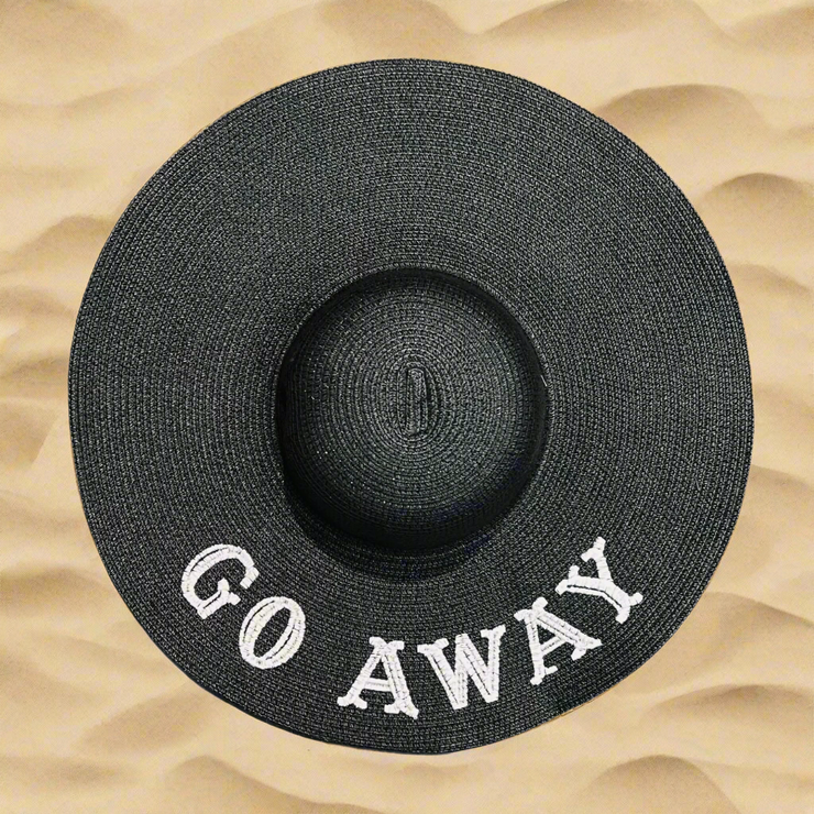 Black straw hat with 'GO AWAY' text on a sandy background