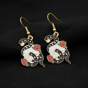 Snake and rose earrings on a black background