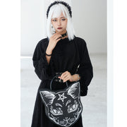 Person holding a black bag with a white cat design and pentagram symbol.