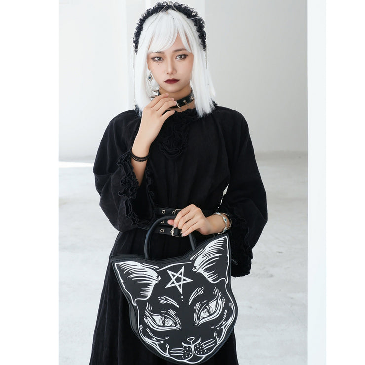 Person holding a black bag with a white cat design and pentagram symbol.