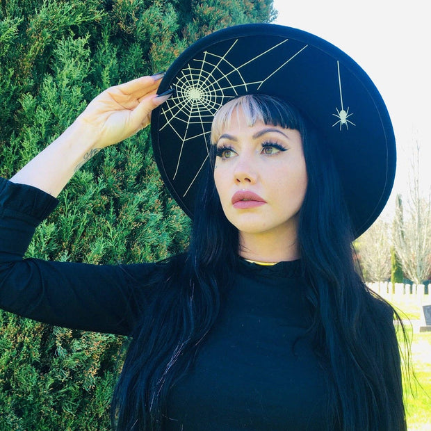 Woman wearing a black hat with spider web design outdoors