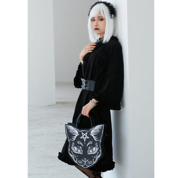 Person holding a black tote bag with a cat design against a white background