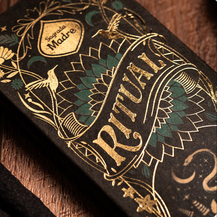 Decorative product packaging with gold and green designs on a wooden surface