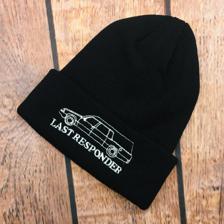 Black beanie with 'Last Responder' text and car graphic on a wooden surface