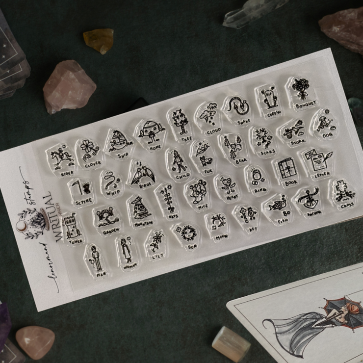 Sheet of clear stamps with various designs on a dark surface with crystals and cards.