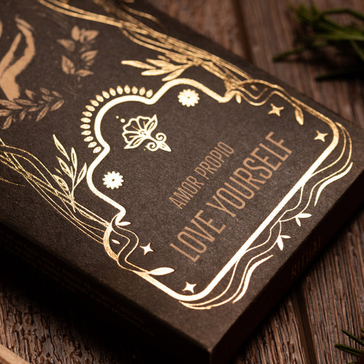 Incense packaging with gold embossed text and decorative elements on a wooden surface