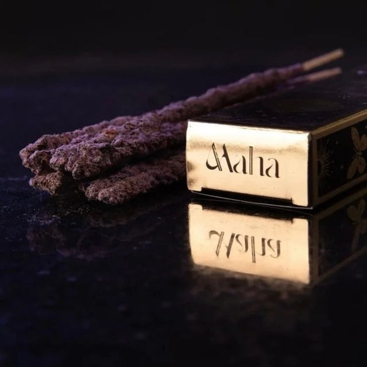 Incense sticks with a Maha box on a reflective surface