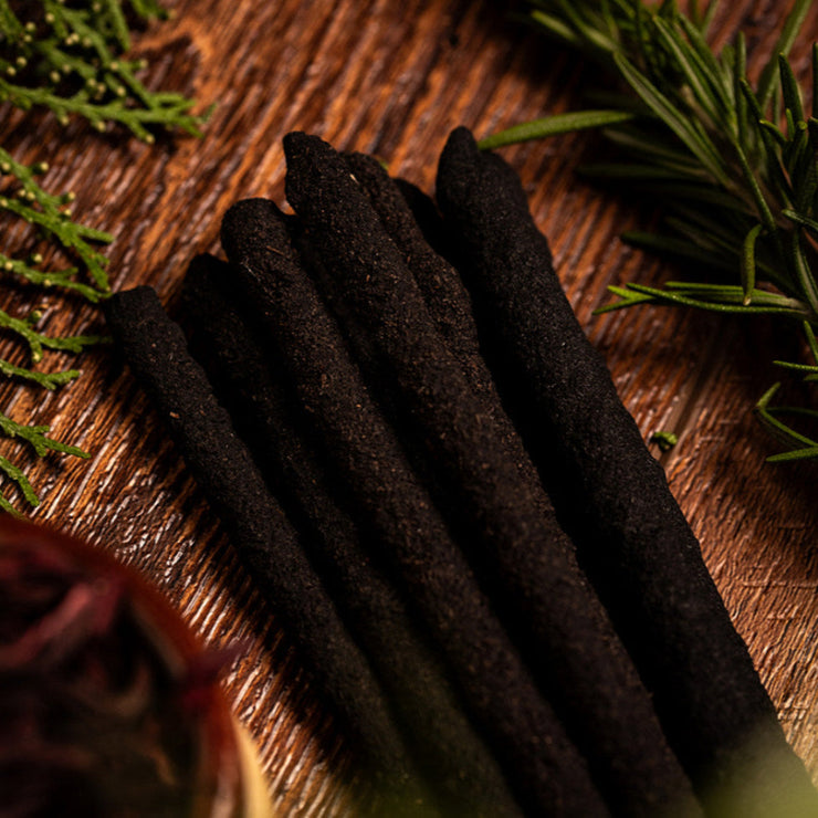 Incense sticks on a wooden surface with green leaves