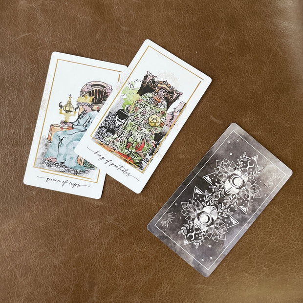 Two tarot cards on a brown leather surface with a third card partially visible.