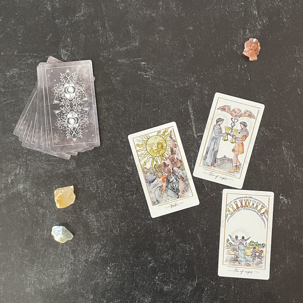 Set of tarot cards on a dark surface with crystals