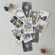 Collection of tarot cards on a light surface with crystals around