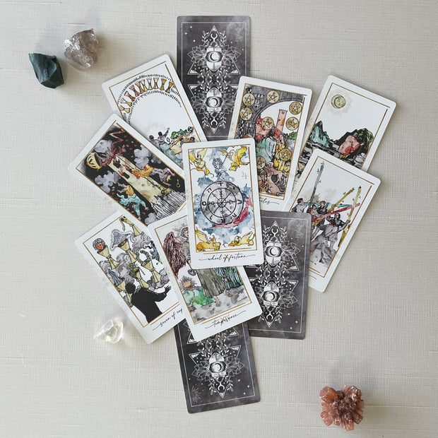 Collection of tarot cards on a light surface with crystals around