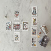 Set of tarot cards on a marble surface with crystals and a candle.