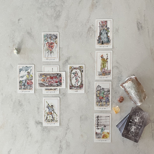 Set of tarot cards on a marble surface with crystals and a candle.