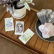 Tarot cards on a wooden surface with a plant and crystal rock.