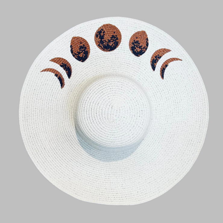 White sun hat with embroidered moon phase designs on a gray background
