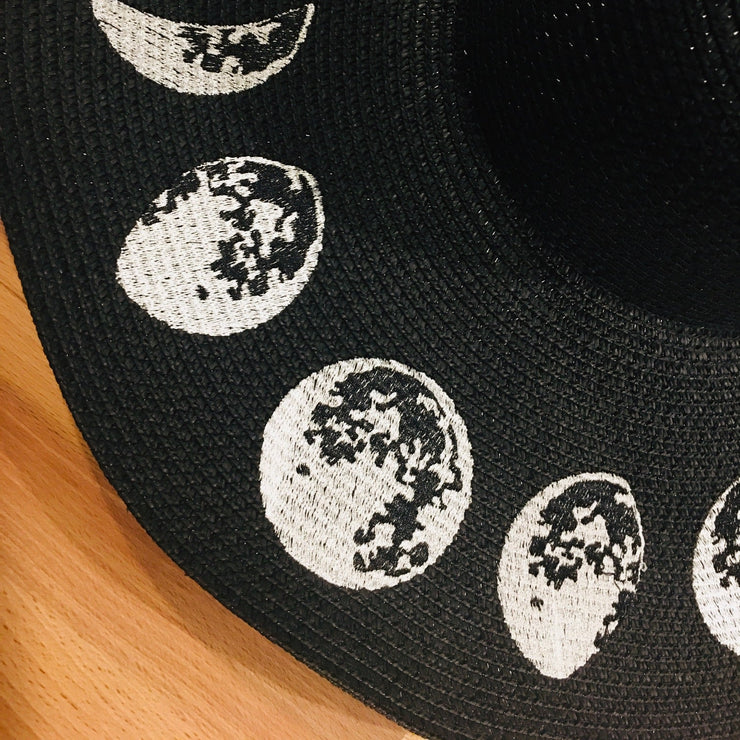 Black sock with white moon phases on a wooden surface