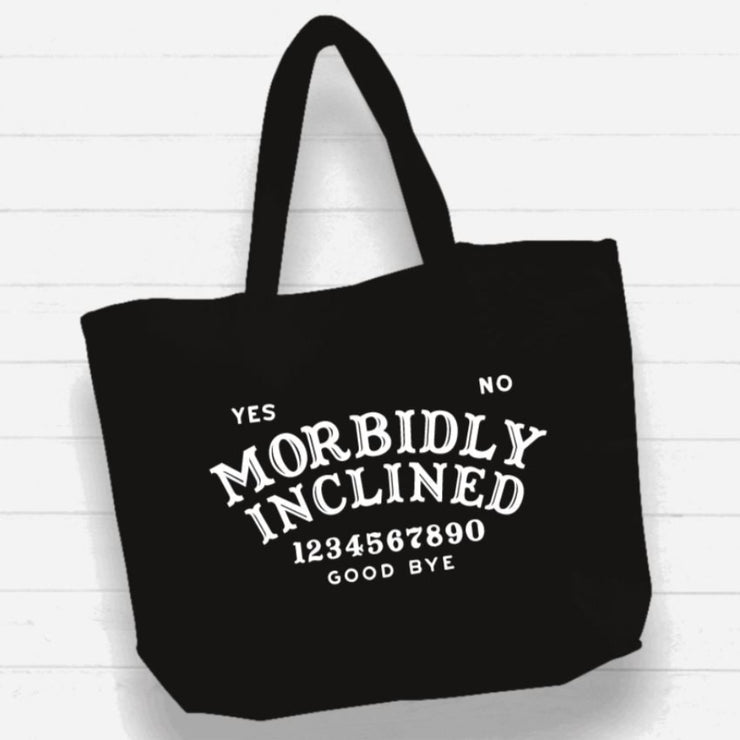 Black tote bag with white text on a light wooden background