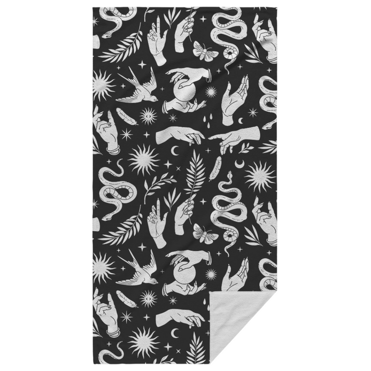 White mystical pattern featuring hands, snakes, suns, moons, crystal balls, swallows, plants, and moths on a black beach towel. Perfect for adding a touch of celestial elegance to any beach or lounging occasion.