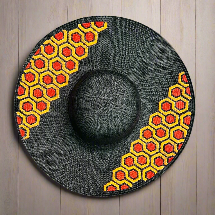 Black straw hat with red and yellow geometric pattern on a wooden surface